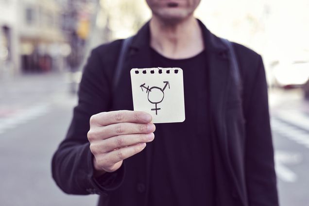 A person holds up a transgender symbol on paper
