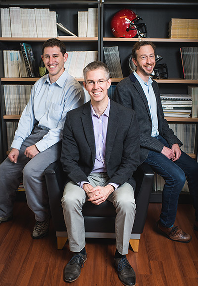 Group portrait of Boston University researchers Jonathan Cherry, Thor Stein and Jesse Mez sitting in front of a bookcase