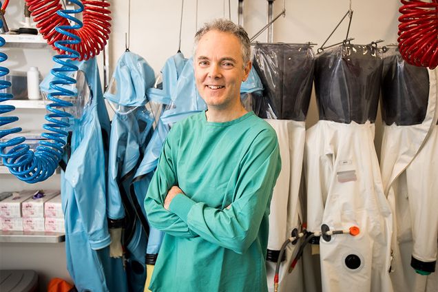 Robert Davey, infectious diseases researcher at the Boston University National Emerging Infectious Diseases Laboratories (NEIDL), poses for a portrait in front of hazmat suits like the ones he wears while conducting Biosafety Level 4 research in the NEIDL laboratory.