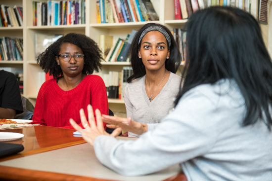 Shadae Leslie (COM'20) at left, and Nneka Oyigbo (CAS'20) listen to faculty member Sucharita Gupal