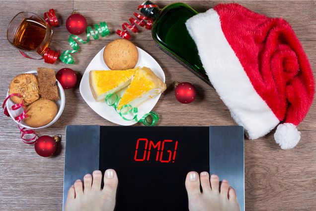female feet on digital scale surrounded by christmas food and decorations