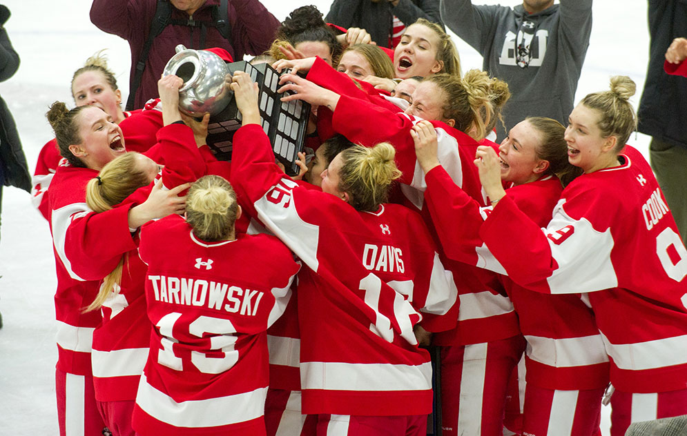 Members of the BU Terriers women's ice hockey team celebrate and carry the Beanpot trophy after winning the 41st annual Beanpot championship.