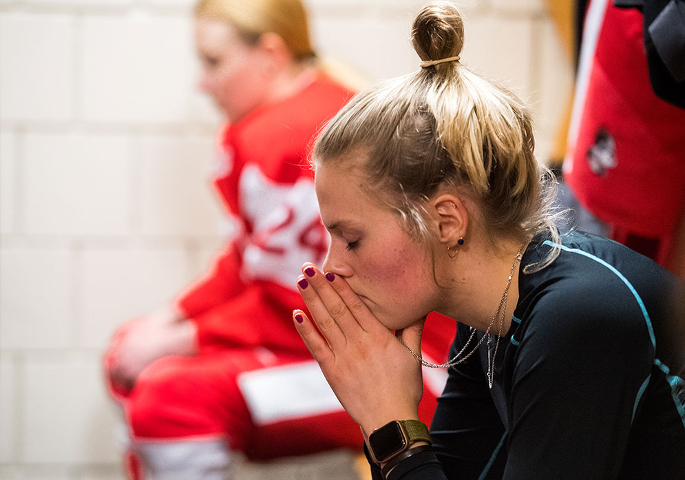 BU women's ice hockey player Abbey Stanley prays silently holding a necklace in the locker room before the Beanpot championship game.