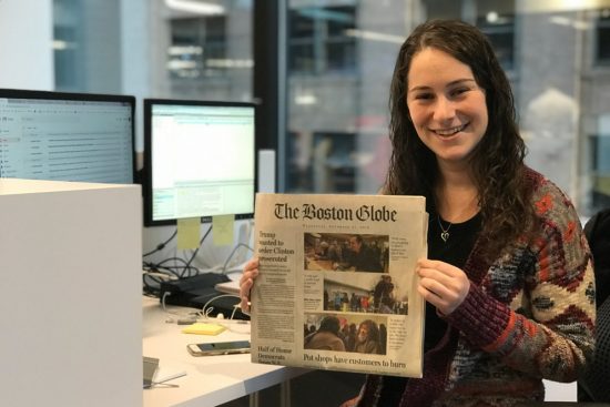 Felicia Gans holds up a paper copy of the Boston Globe 