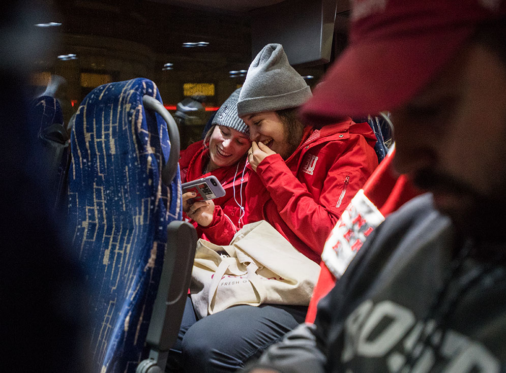 BU women's ice hockey players Abbey Stanley and Nara Elia watching videos on their phone on the team bus.