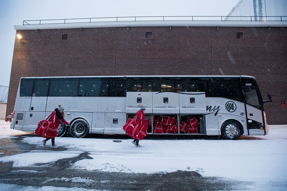 BU Terriers women's hockey players pick up their hockey bags from the team bus before entering Bright-Landry Hockey Cente.