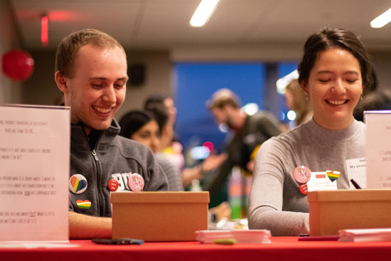 Matthew Walker and Caroline Jens sitting behind a red table and laughing