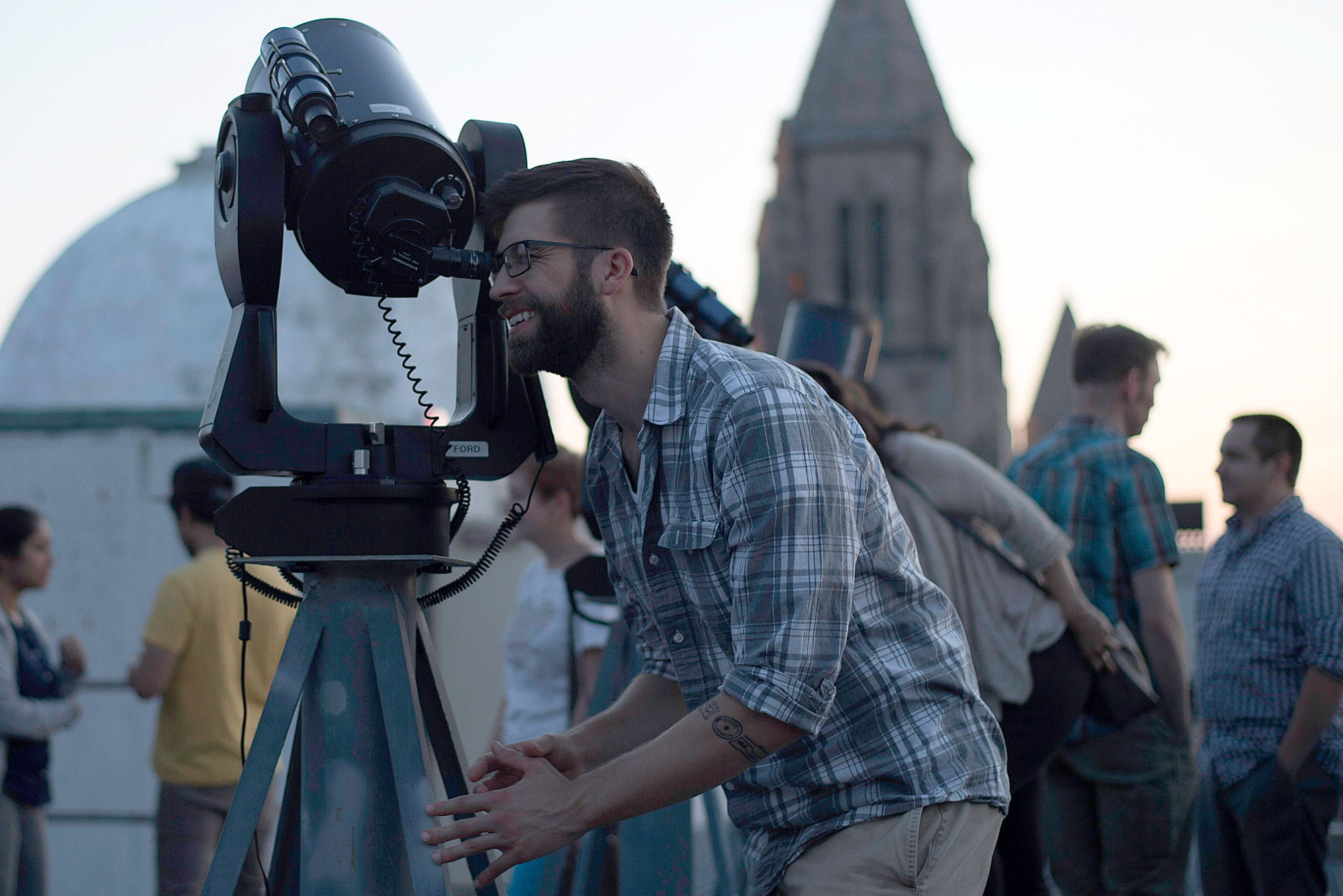 A student peers through a telescope at the Boston University Coit Observatory.