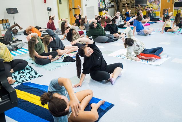 students stretch while sitting on the cross-legged on the ground