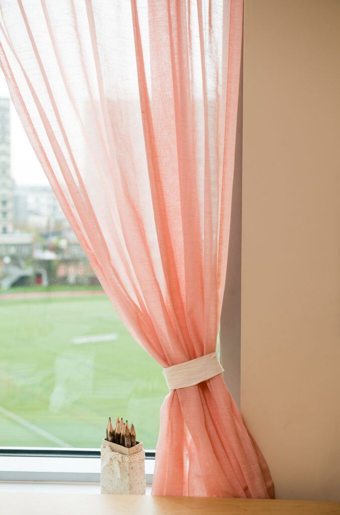 A sheer pink curtain draws attention to views of Nickerson field 