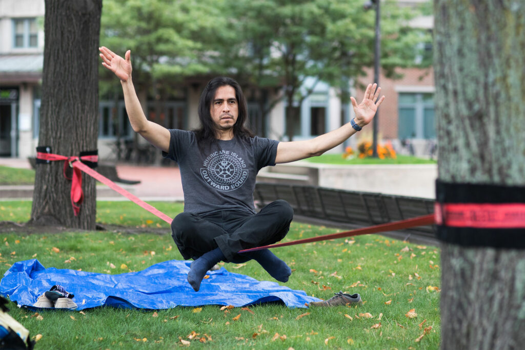 FitRec climbing instructor Victor Pachas keeps his balance while slacklining in front of Metcalf Science Center.