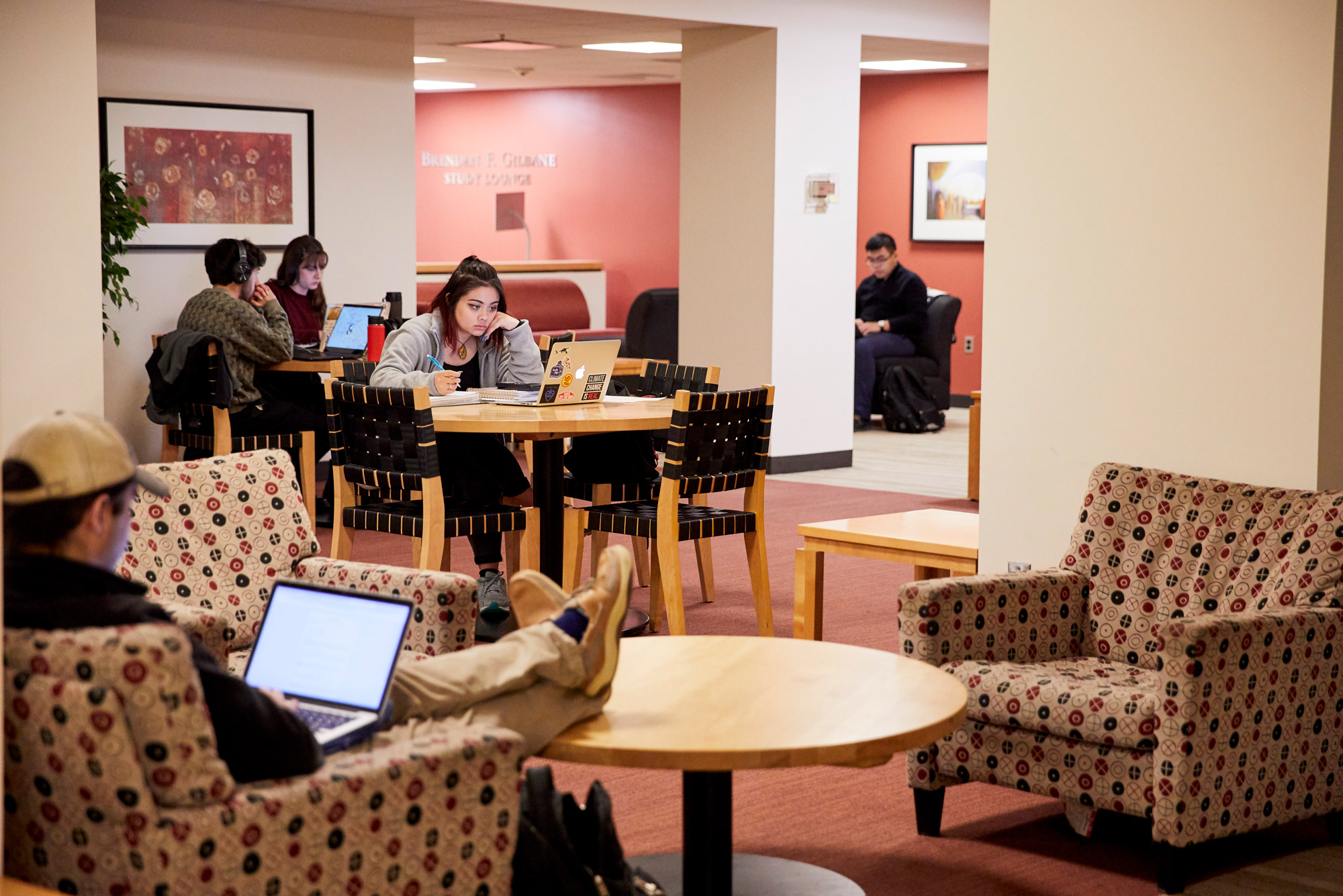 Photo of a student studying intently as they sit at a wooden table.