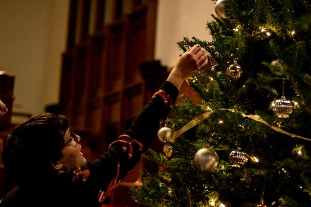 A student hangs ornaments on a Christmas tree in Marsh Chapel