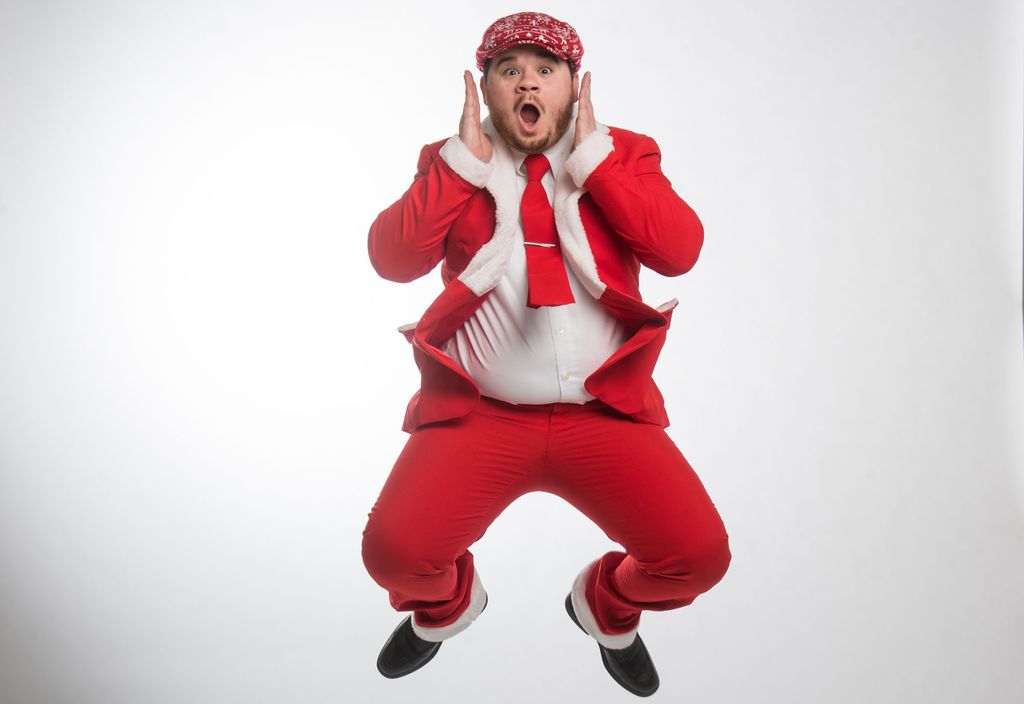 Kyle Benedicts leaps in the air while wearing a red santa inspired suit