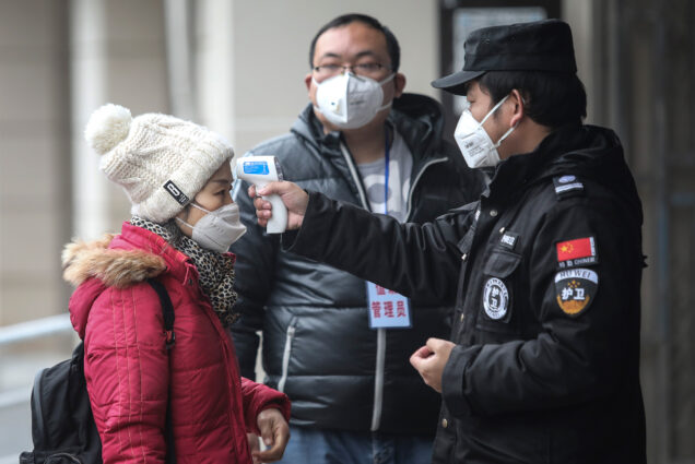 Security personnel check the temperature of a passenger in the Wharf at the Yangtze River on January 22, 2020 in Wuhan, Hubei province, China.