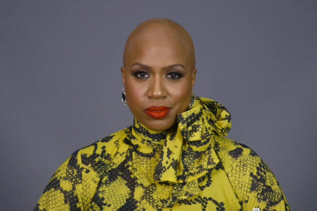 A portrait of Ayanna Pressley where she reveals her bald head as a result of Alopecia Areata