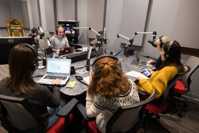 Photo of students at WBTU during the station's election night coverage on November 6, 2018; image shows five students seated around a table with sound equipment.