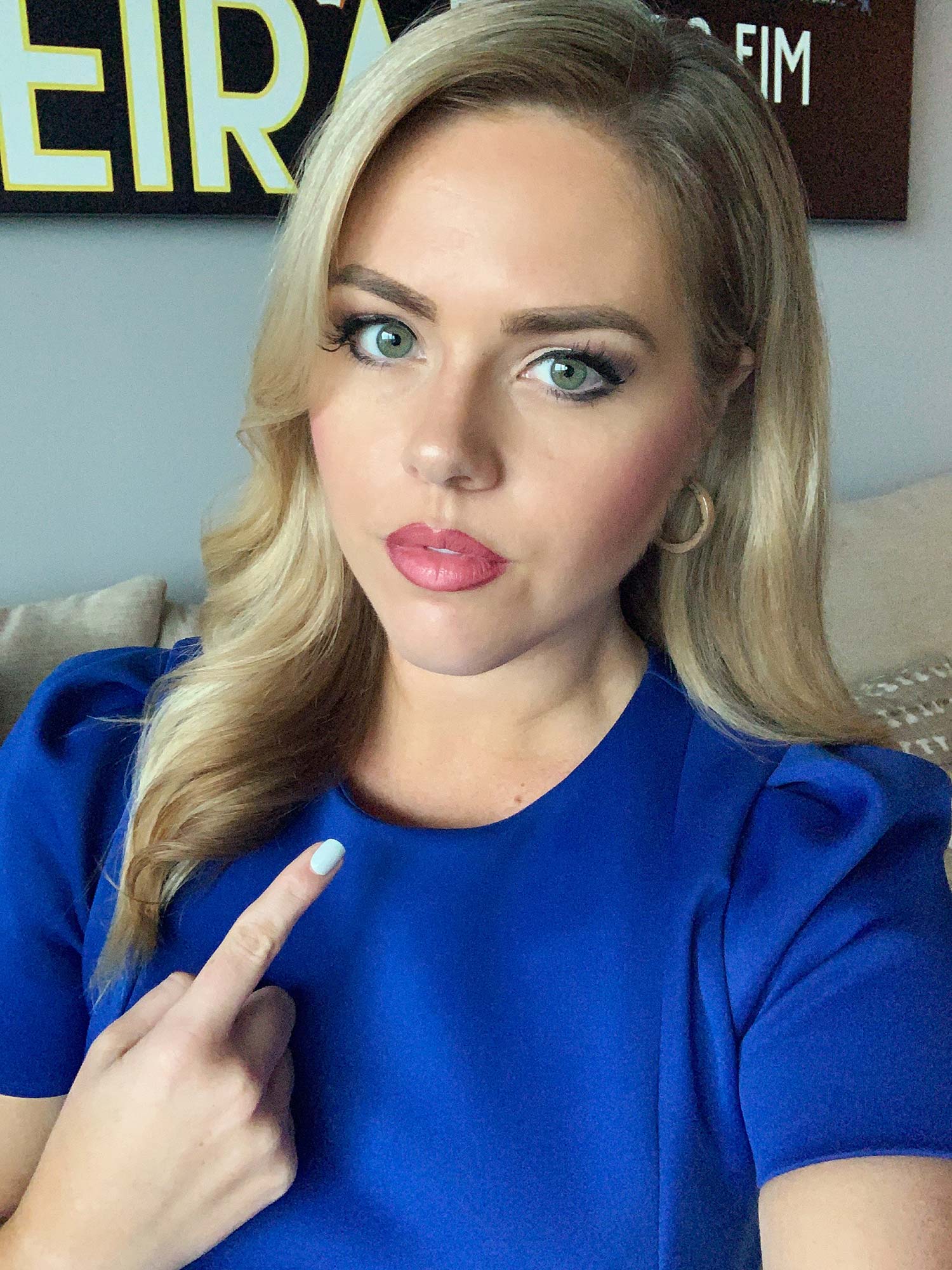Selfie of Victoria Price that went viral. In the post she points to her neck and wears a bright blue dress.