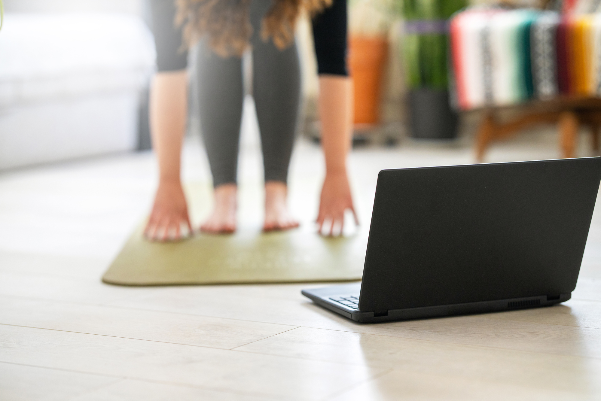 A photo of a person doing yoga in front of an open laptop