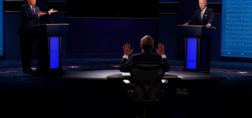 Photo of President Trump and Former VP Joe Biden debating on stage on September 29. In the foreground, the back of Chris Wallace is seen, his hands are raised.