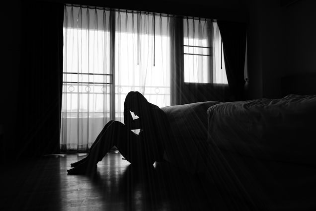 silhouette of depressed man sitting on the floor