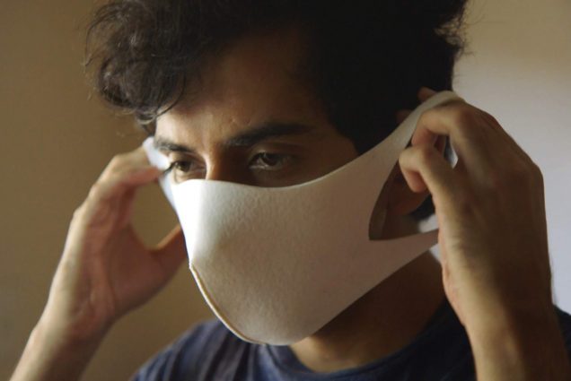 Image of a young person pulling a white mask over their face.