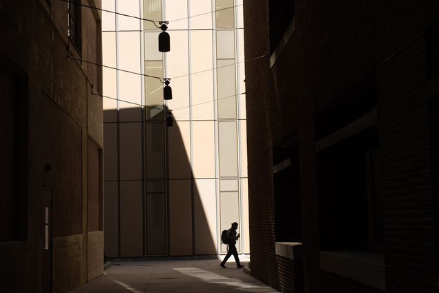 Photo of the sun casting harsh shadows behind Kilachand CILSE on September 21. A single person with a backpack walks by and is seen in silhouette.