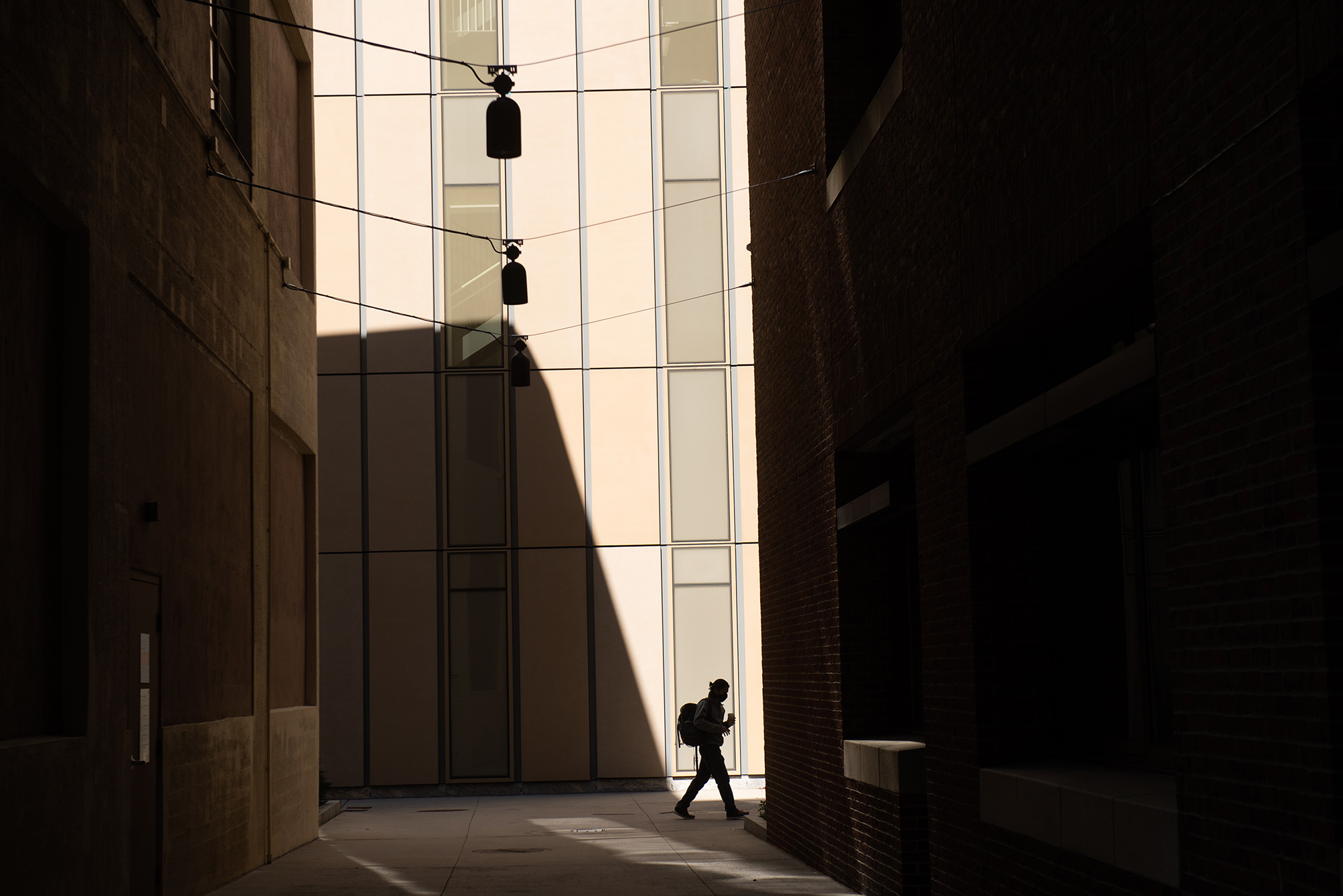 Photo of the sun casting harsh shadows behind Kilachand CILSE on September 21. A single person with a backpack walks by and is seen in silhouette.