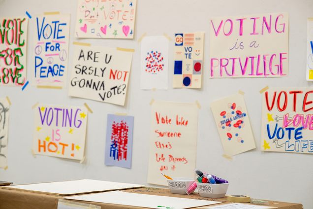 Photo of the School of Visual Arts pop up show "The Vote Show!" created to help spread awareness on the importance of voting. SVA students, faculty and staff are making posters to encourage people to vote on November 3rd. In the photos, a bunch of paper signs with phrases such as "voting is a privilege" and "vote" written on them in bright colored marker.