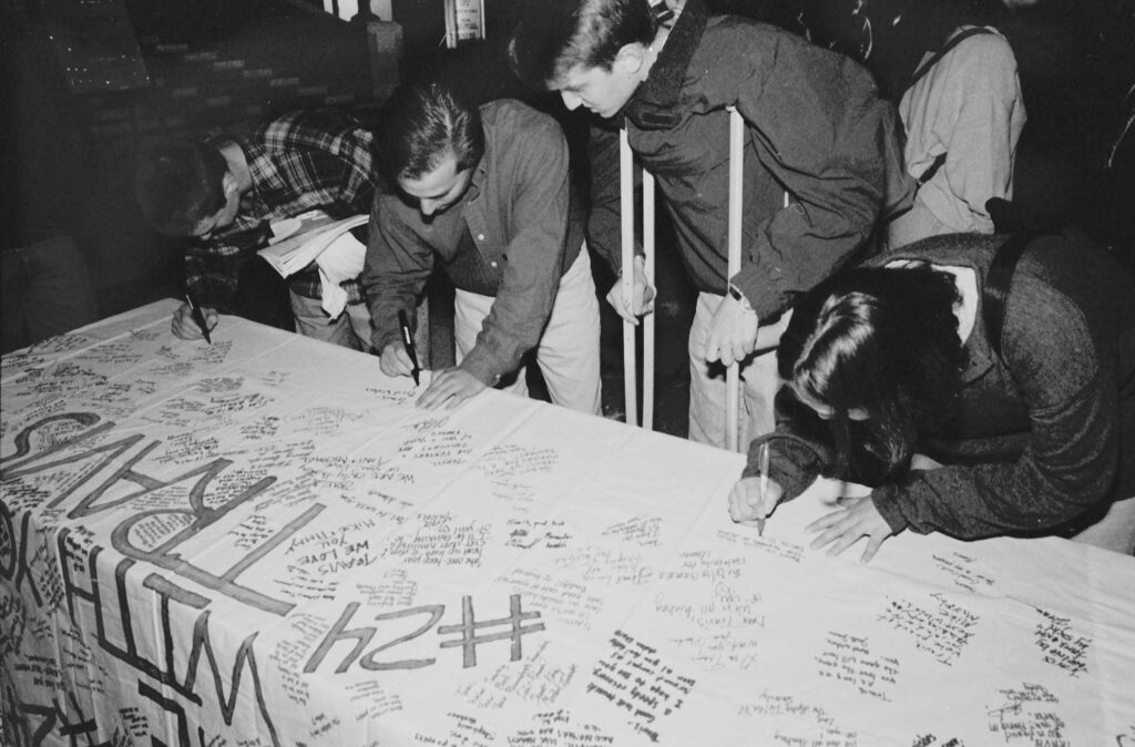Boston University students write well wishes to Travis Roy on a banner following his injury in 1995