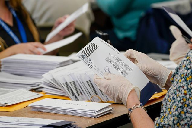 Photo of a pair of gloved hands counting ballots. Piles of ballots are seen in the background. These are municipal workers extracting Luzerne County ballots from their envelopes, Wednesday, Nov. 4, 2020, in Wilkes-Barre, Pa.