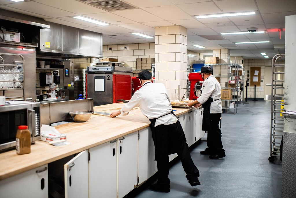 Photo of two kitchen staff in chef coats and aprons working in the newly renovated kitchens at the Food Hall.