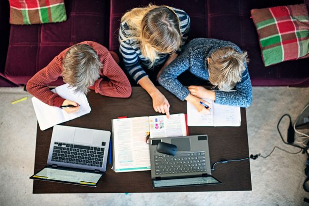 A photo of a mother helping her two children with remote learning.