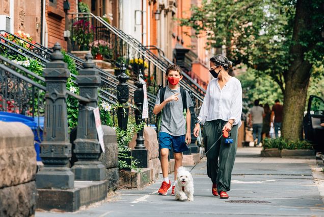 A photo of a mother and child walking down the street wearing masks