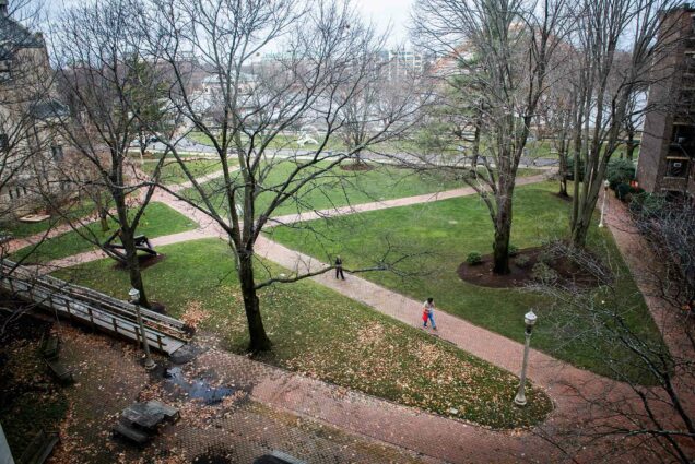 Photo of brick paths criss-crossing at BU Beach, a few people walk down the path. The trees are bare and are without leaves.