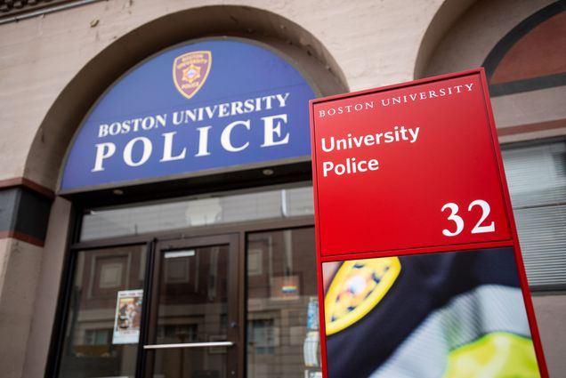 Photo of the entrance of the Boston University Police building, its name written on a blue arched sign above the doorway. A red sign that reads "University police" with a larger number 3 is seen in the foreground.