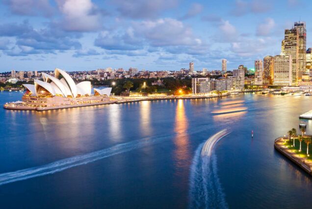 The Circular Quay neighborhood in Sydney, Australia taken from the Sydney Harbour Bridge just after sunset showing the Sydney Opera House on the left.