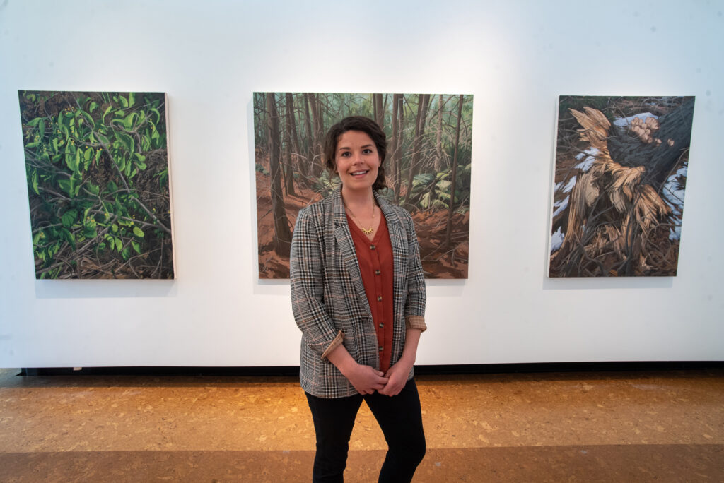 Amanda Hawkins (CFA’21) with her paintings Oriental Bittersweet (from left), Former Property Line, and Disturbance #3, which examine the interaction between humans and nature.