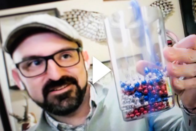 A photo of T.J. McKenna holding up a beaker. A white video play button is overlayed.