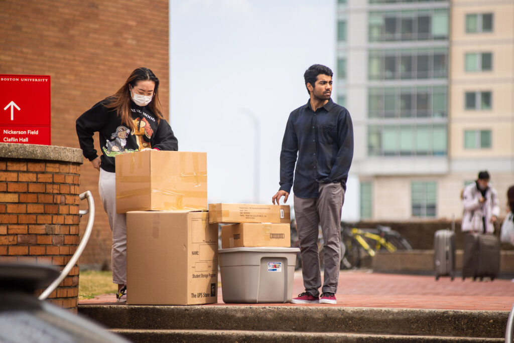 A photo of students waiting to be picked up along with their belongings outside West Campus dormitories