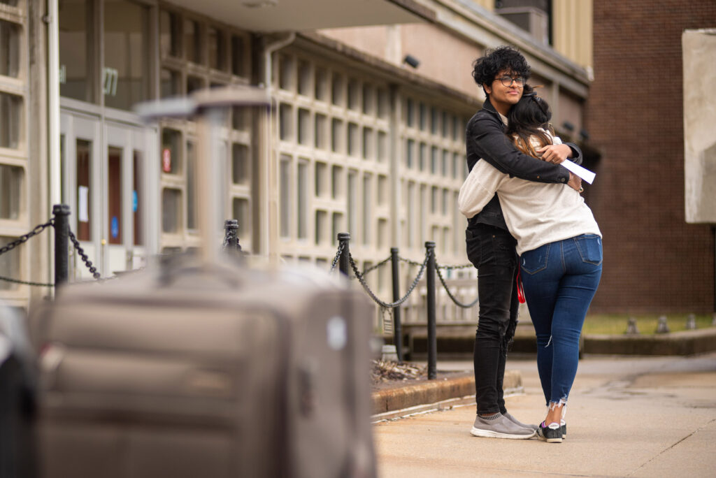 Two students hug outside a West Campus dormitory before departing from campus