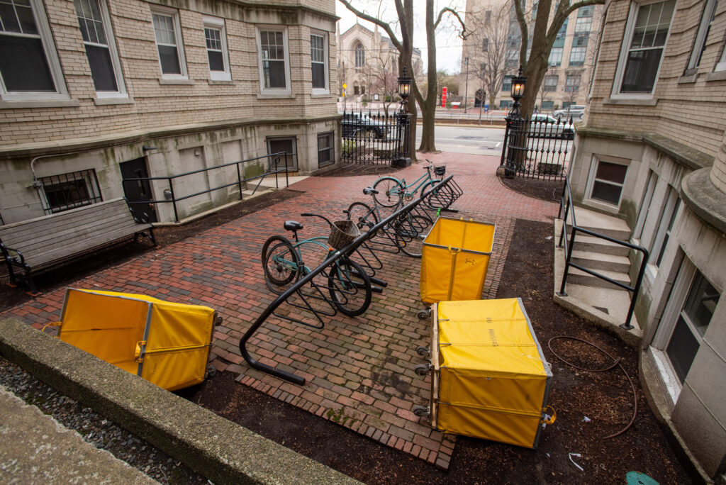 A photo of yellow bins used to move out of dorms standing outside a residence hall on Commonwealth Ave.