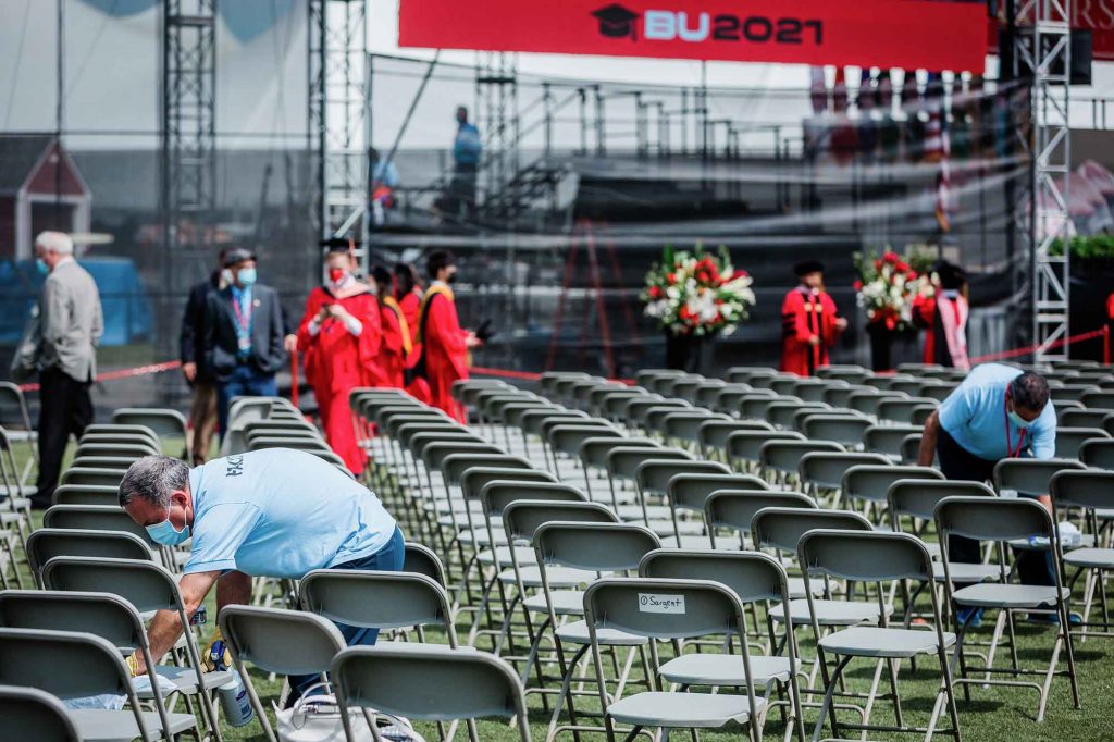 Boston University Facilities staff wipe down and sterilize seats on Nickerson Field in between Commencement ceremonies.