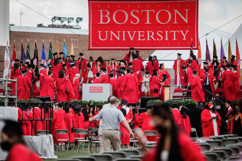 Students flood the stage to celebrate following the 2021 BU Commencement ceremony for undergradte degrees.