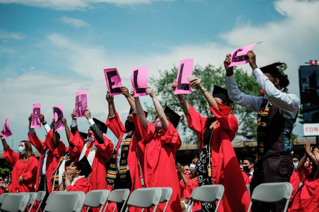 A row of graduating students hold up individual letters that spell the name 'Archelle' during the student speaker address by Archelle Thelemaque at BU's 2021 Commencement.