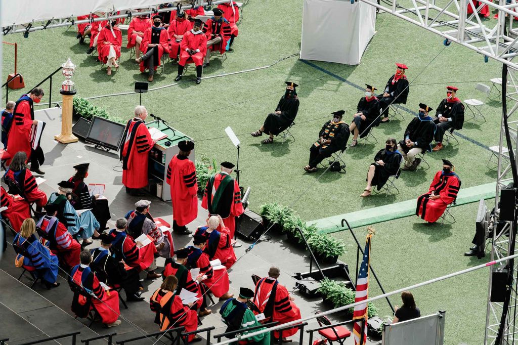 Elevated view of Commencement from the back of the stage while BU President Robert A. Brown speaks at the podium.