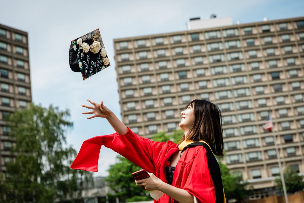 A photo of a student tossing their mortarboard cap up in the air