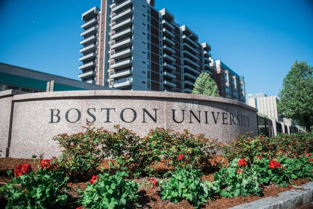 Photo of the “Boston University” sign with red flowers in front.