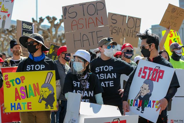 Photo of William Guo, left, Francis Kwok, Henry Lei, right, all of Alameda, and about a thousand demonstrators listen to speakers during an anti-Asian American hate march and rally at San Francisco City Hall in San Francisco, Calif., on Saturday, March 27, 2021. The march, organized by the Chinese Consolidated Benevolent Association, started at city hall and ended at Union Square. They are dressed in fall clothing, many in black t-shirts that say "Stop Asian Hate" and face masks, and cardboard protest signs.