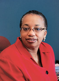 photo of Cassandra Clay (SSW’79). She turns to the left to look at camera and wears a red blazer.